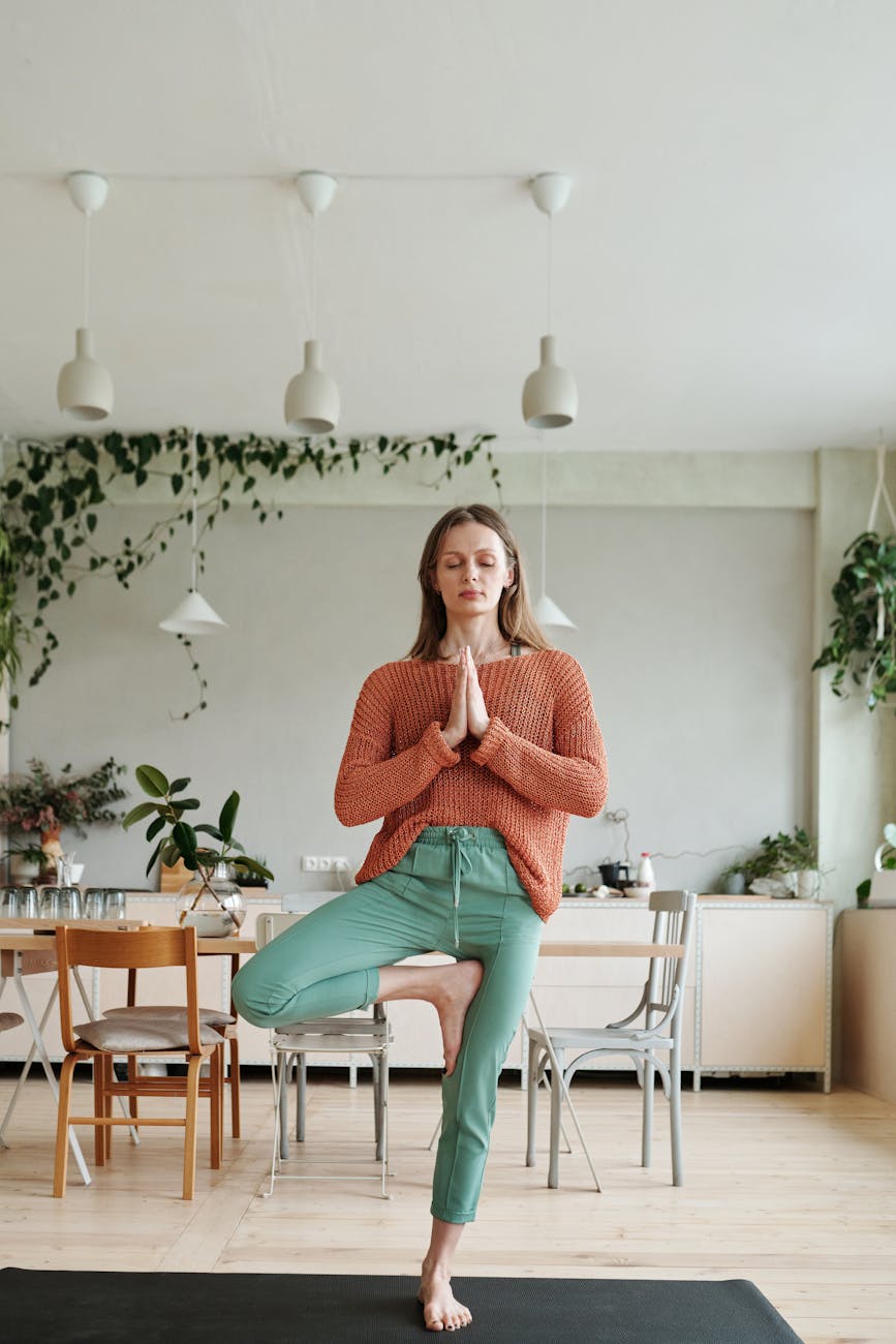 a woman standing on one leg on the yoga mat